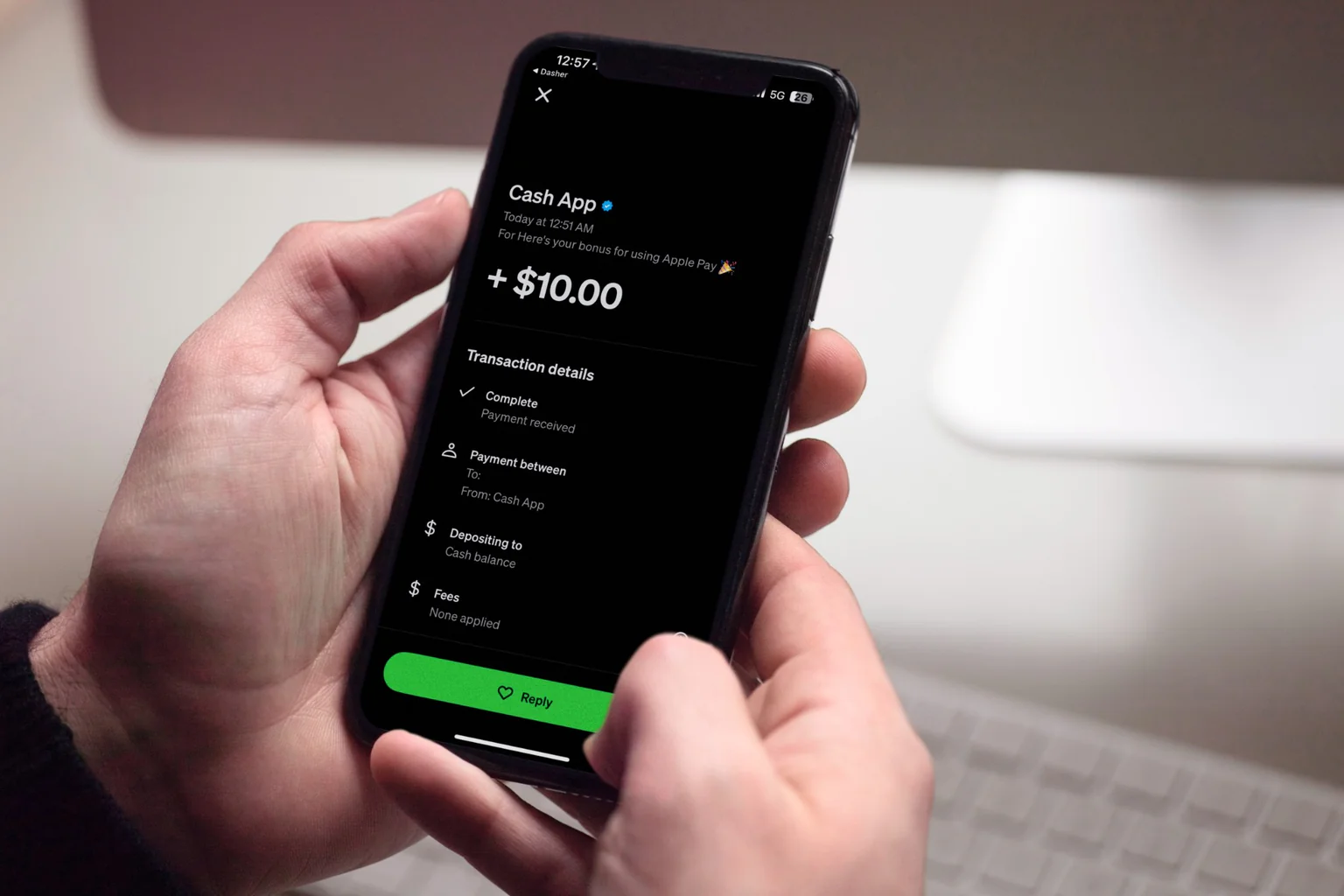 Hands holding a phone showing a $10.00 payment received in Cash App
