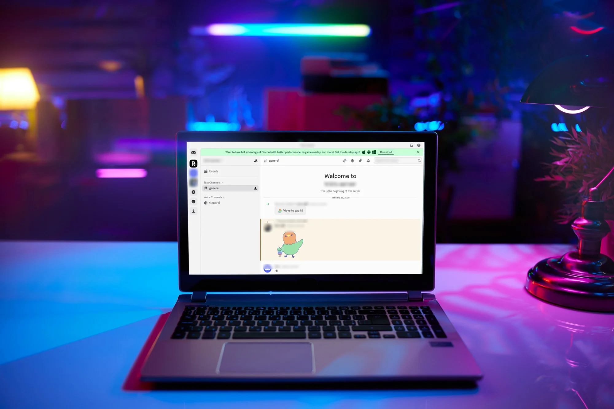 A laptop on a desk in neon light, showing the Discord app with server and user names blurred