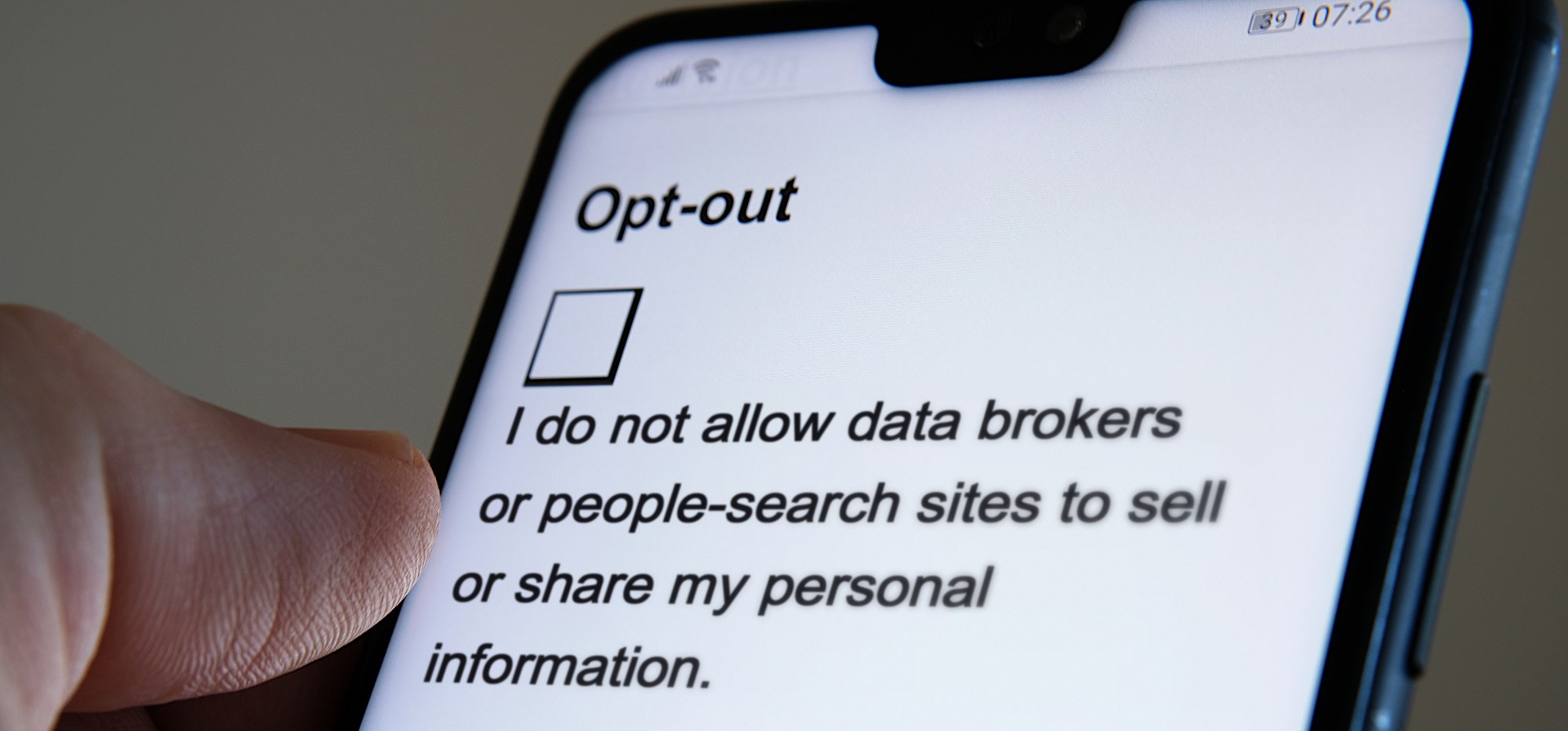 A phone showing an opt-out form with an empty tick box above the line I do not allow data brokers or people-search sites to sell or share my personal information