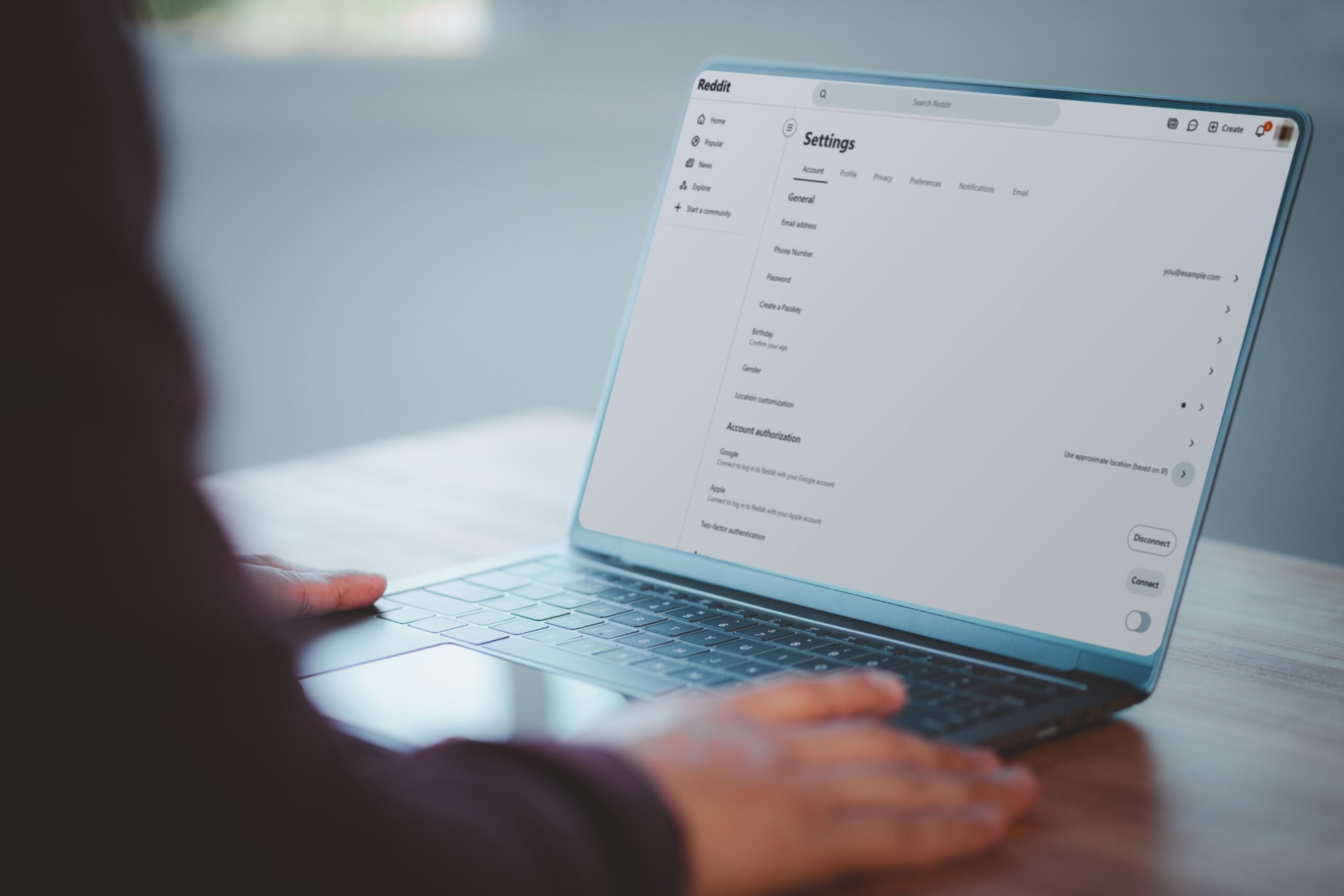 Hands on a laptop open to Reddit's account settings page