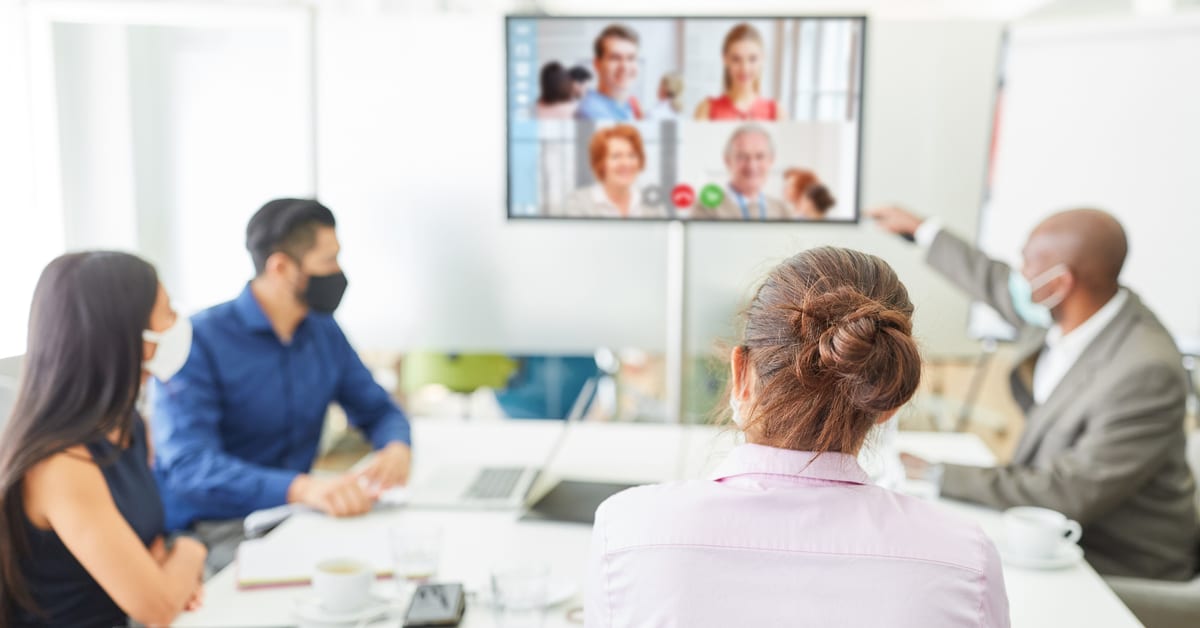 Coworkers in a meeting room on a video call with remote colleagues