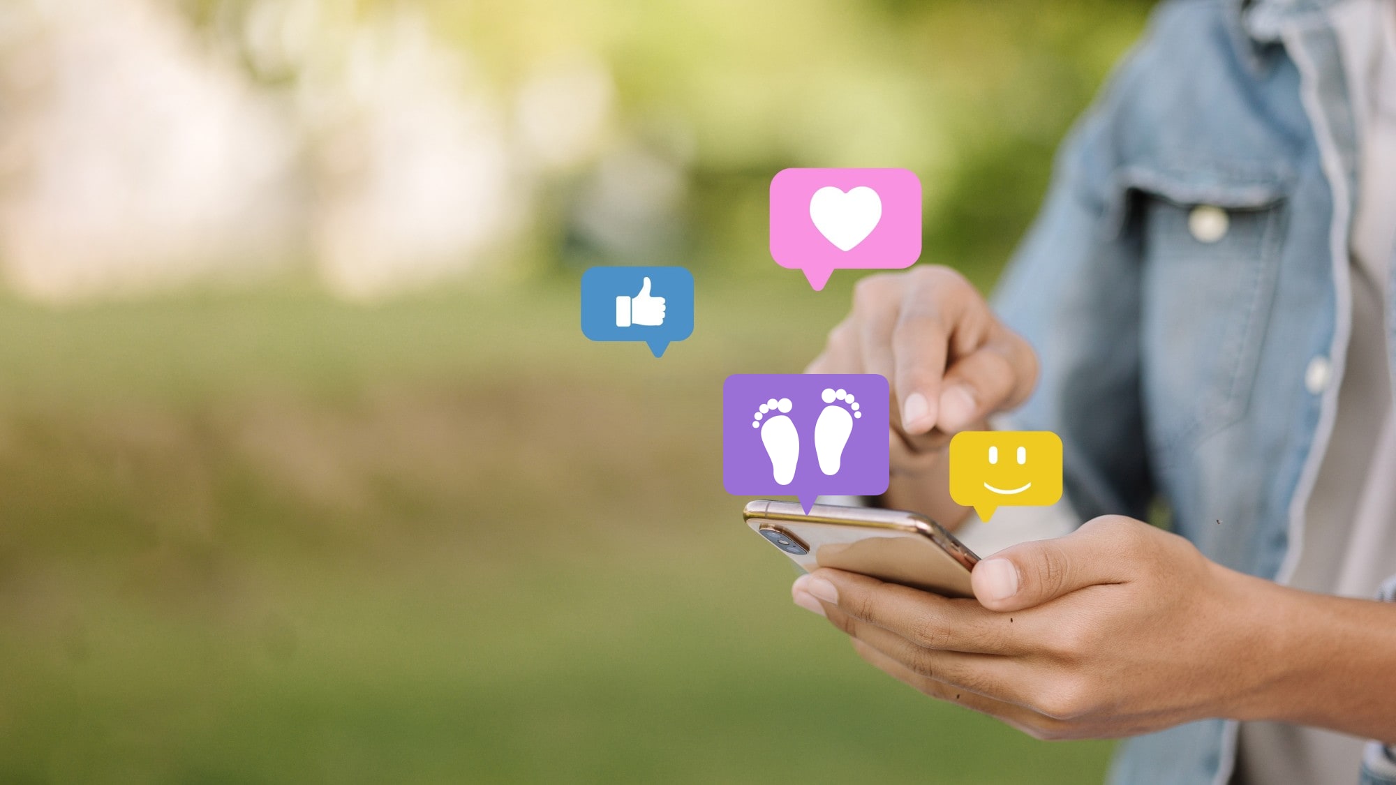 A person holding a smartphone as like, heart, smiley and footprint icons float above the screen